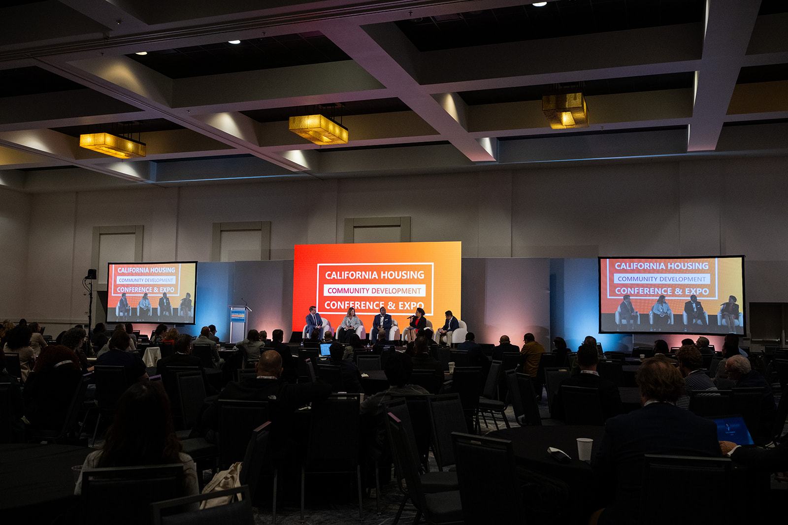 A full ballroom facing the main stage at a housing conference