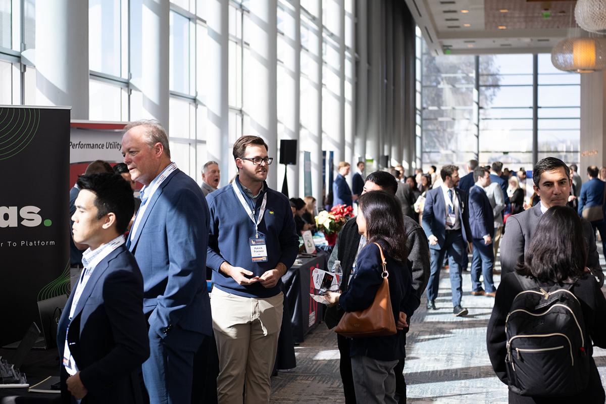 A crowded exhibit concourse lined with exhibitor booths