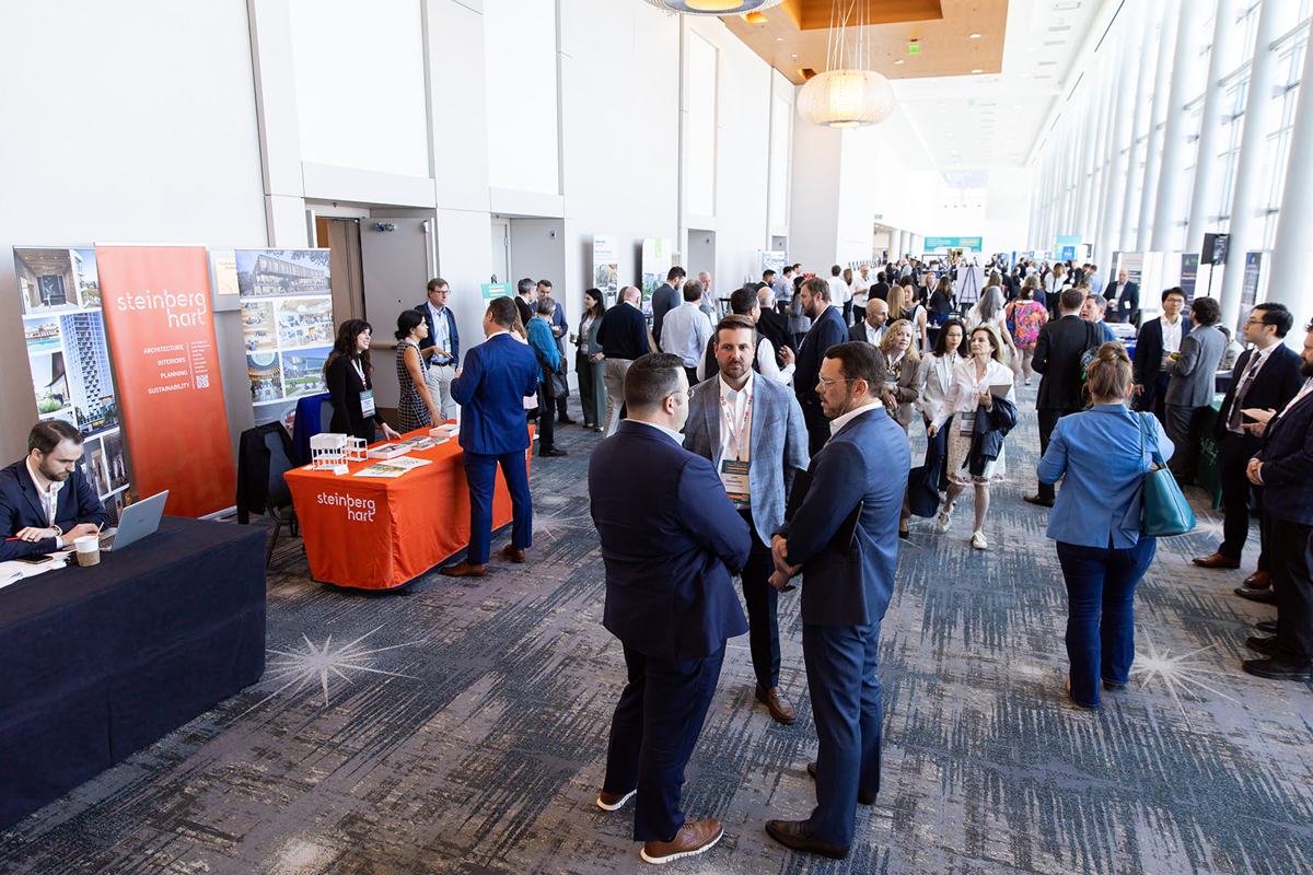 A busy exhibit concourse with exhibitor tables on both sides
