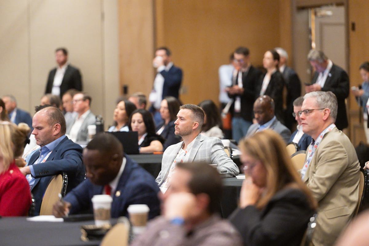 A packed audience at round tables during a session
