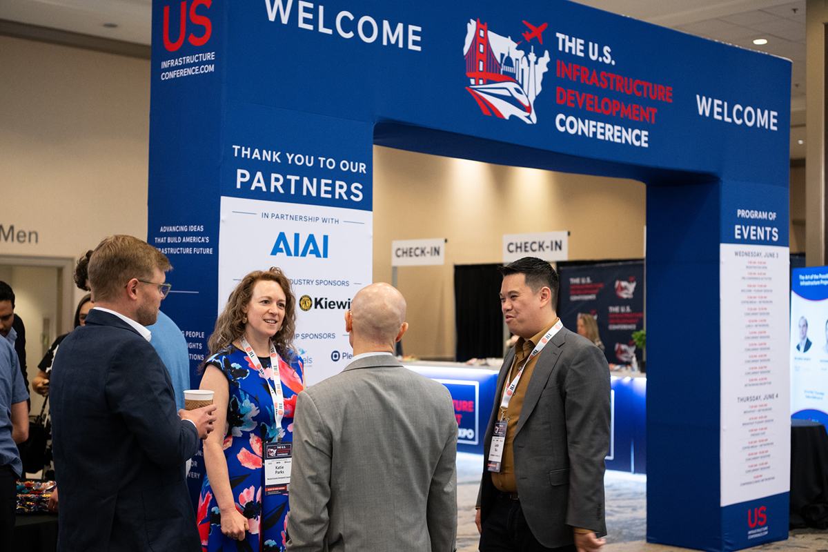 Attendees talking beneath the conference welcome arch